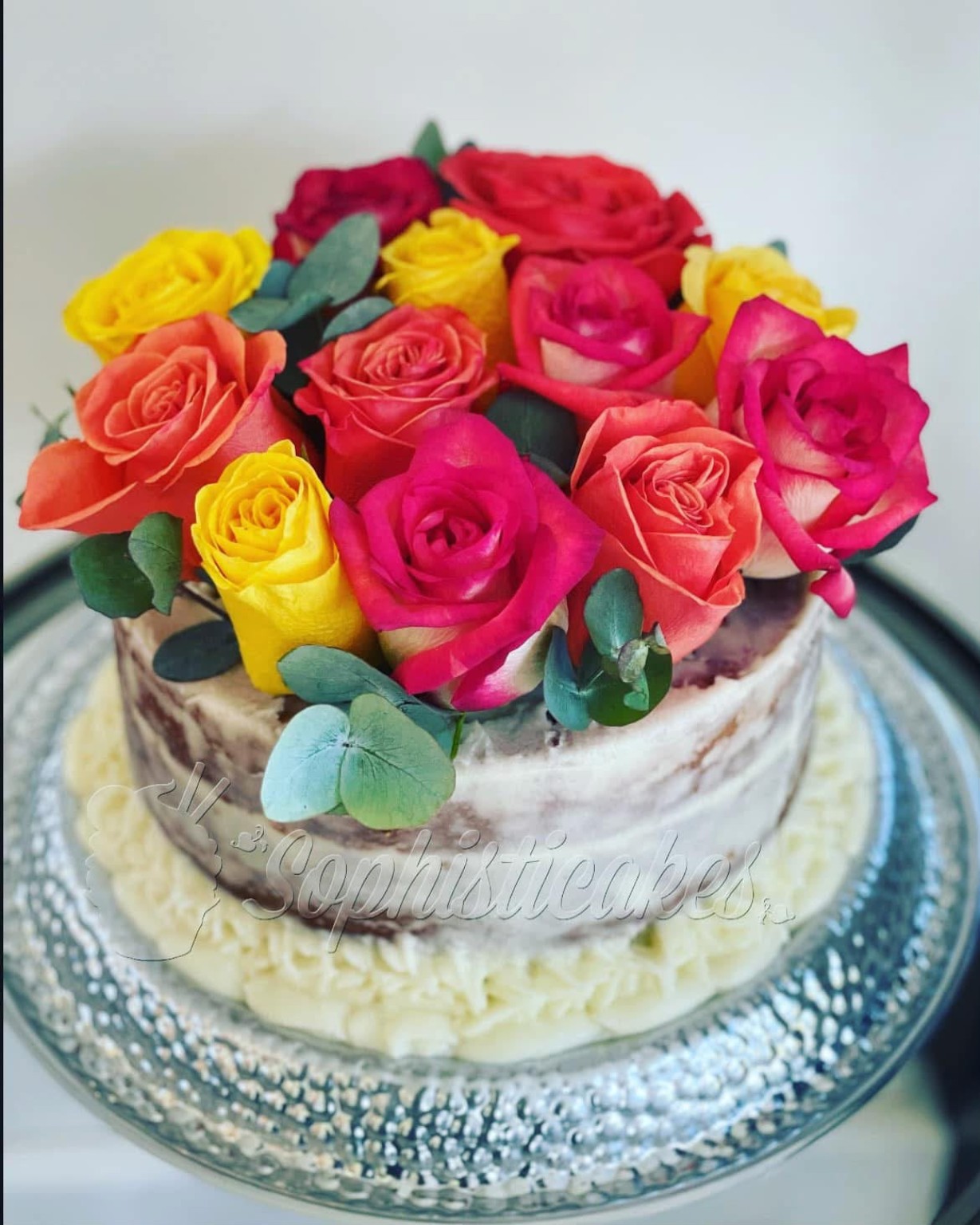Queque decorado con rosas de colores sobre base elegante
