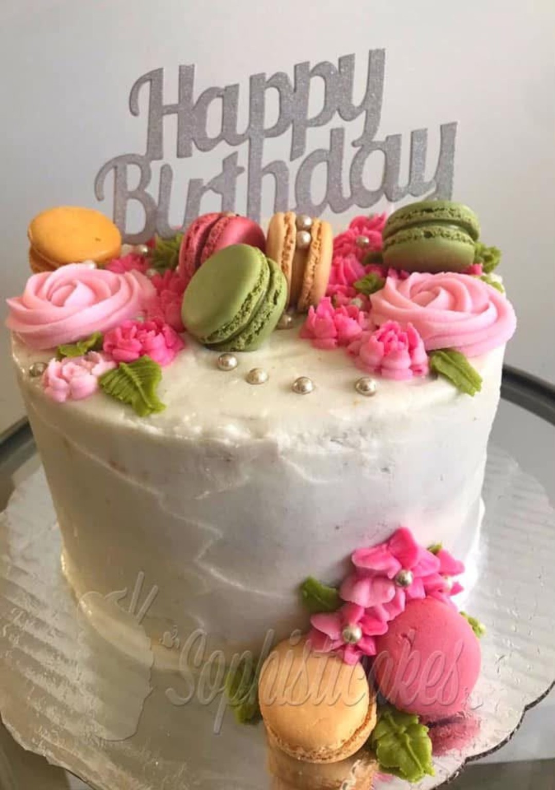 Queque de cumpleaños decorado con macarons, flores rosadas y topper